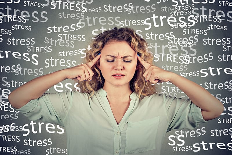 Woman closing her eyes with the words stress floating around her